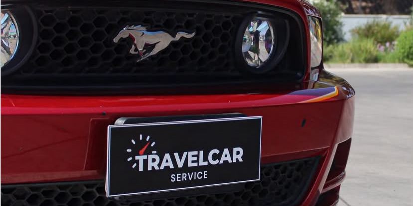 Auto rojo con la placa de TravelCar Service en el parachoques